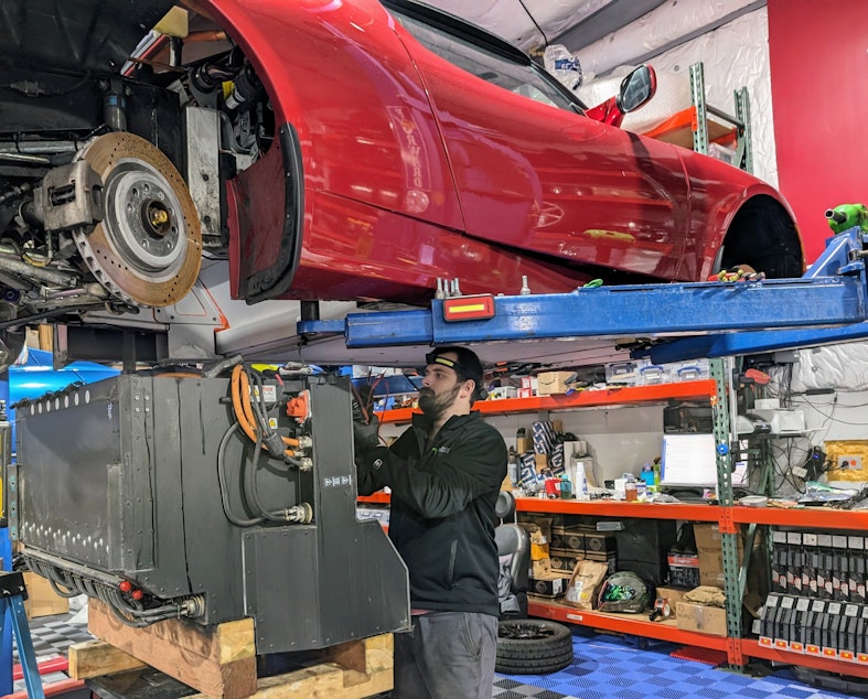 caption: Austin Medlock works on a Tesla battery.