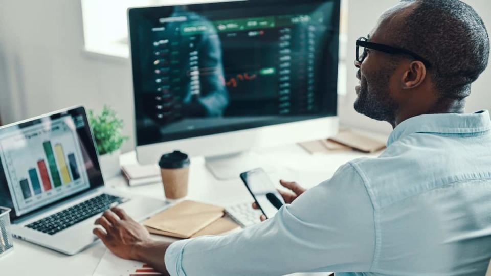 man in shirt using computer and smiling while working in the office