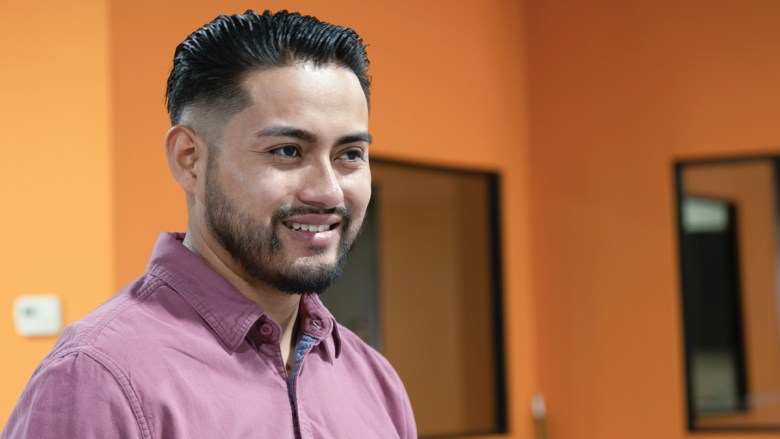 Smiling man with beard and red shirt.