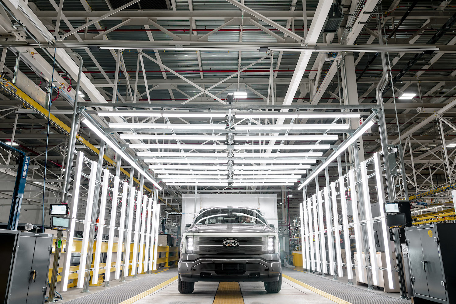 Ford F-150 Lightning at Ford's Rouge Electric Vehicle Center in a factory with bright lights in the back.