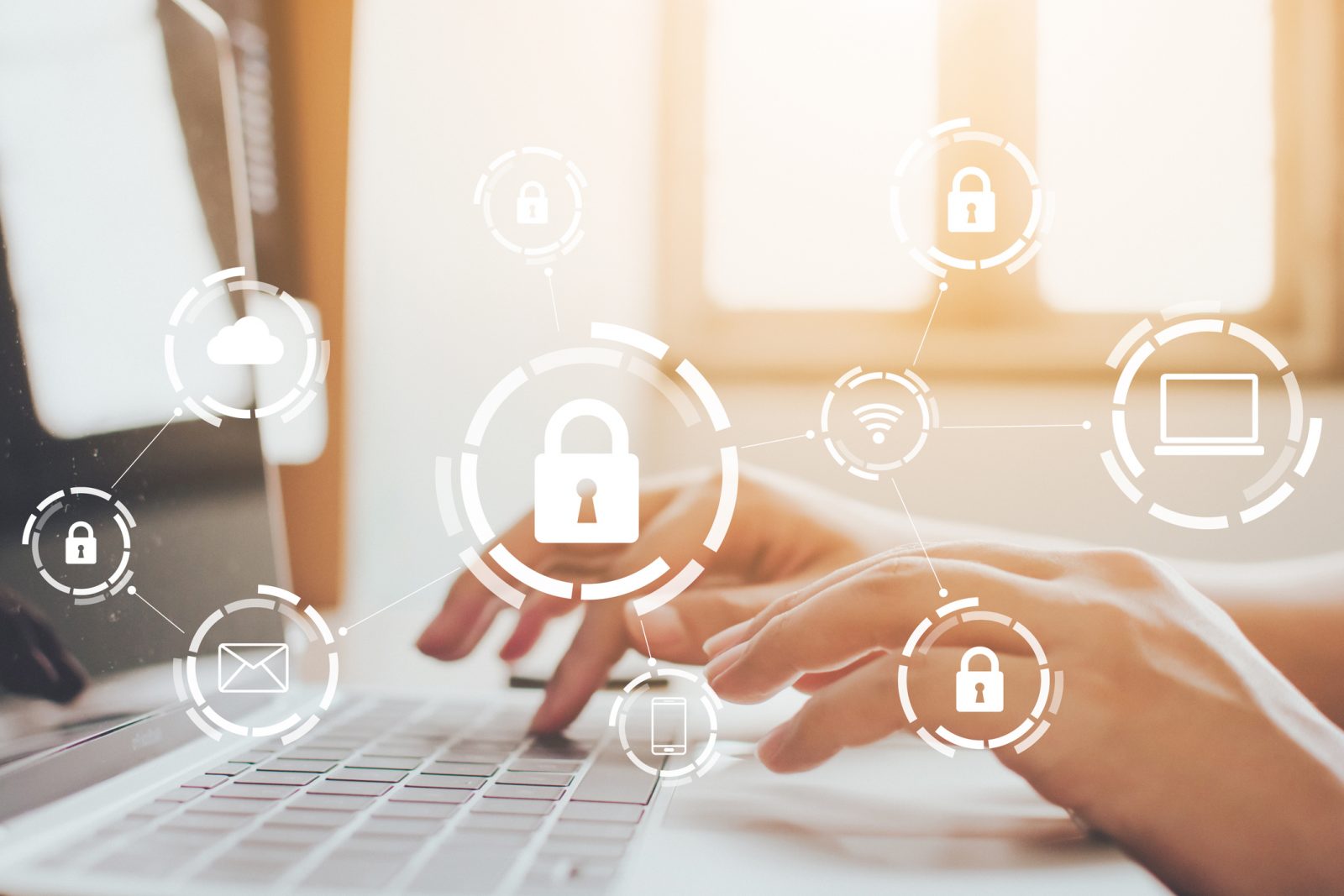 Closeup view of hands typing on a laptop with cybersecurity icons floating above them.