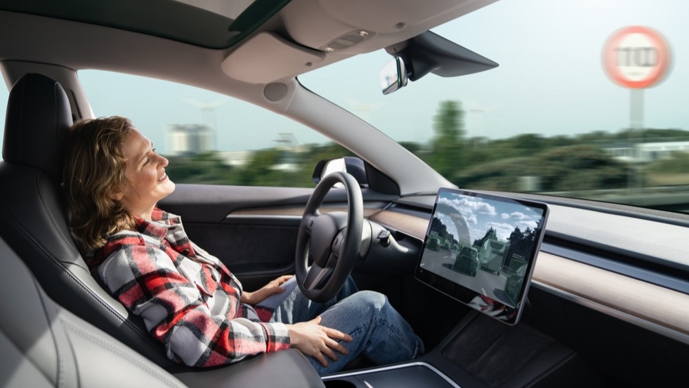 A woman sits back and smiles in the driving seat of a car.