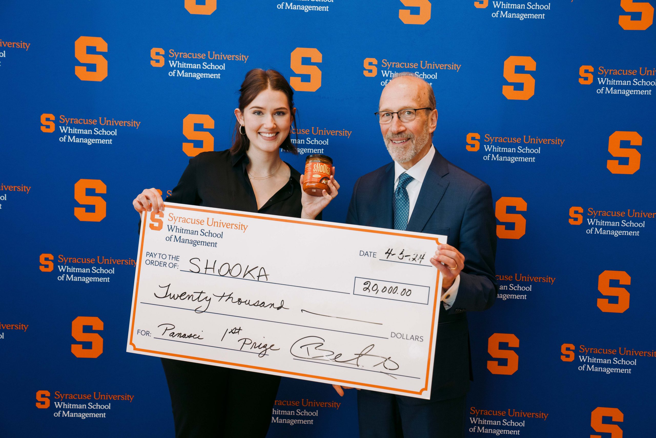 Two people standing next to one another holding an oversized check