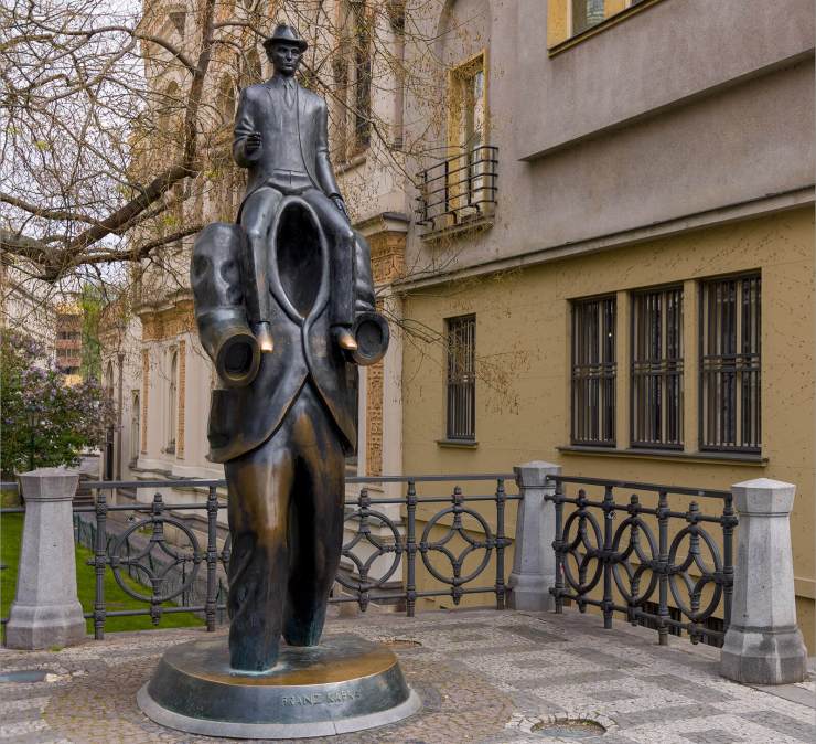 The statue of Franz Kafka in Prague, Czech Republic with tourists.