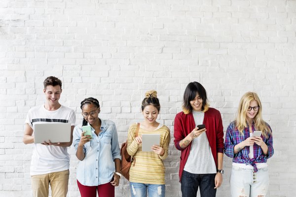 A group of young people on social media on laptops, tablets, and smartphones