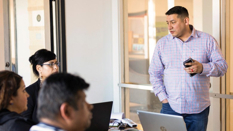 Man stands in front of a group of people on laptops.