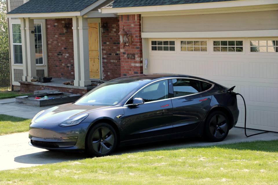 Tesla electric car in driveway being charged at a home with an EV charger in  residential neighborhood, Moscow, Idaho. (Photo by: Don & Melinda Crawford/UCG/Universal Images Group via Getty Images)