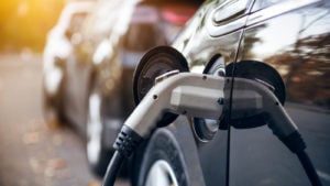 A photo of an electric car with the charger plugged in.