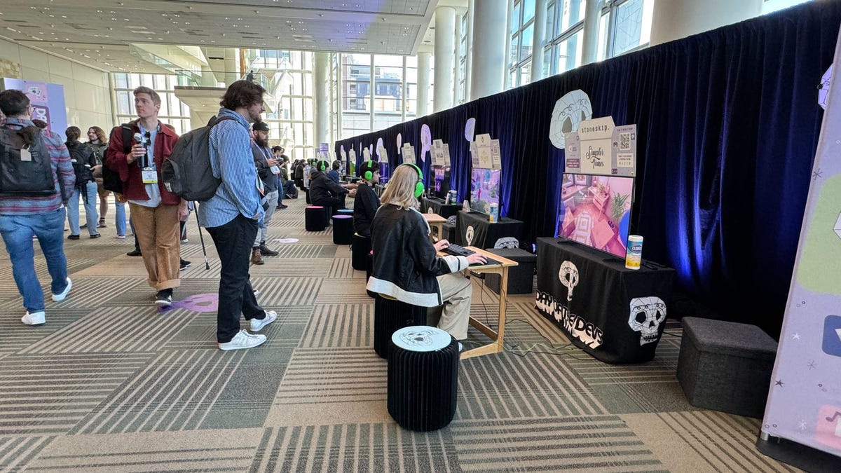 A group of people line up in front of game stations for new indie games.