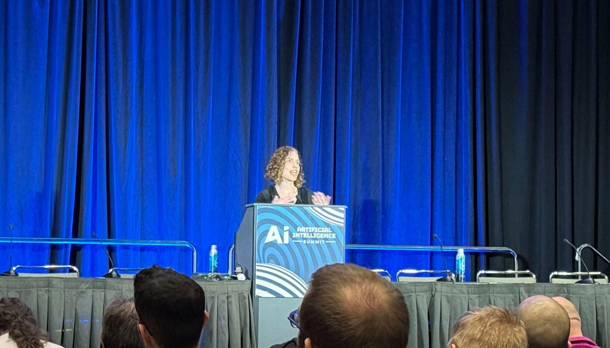 A woman stands at a podium labeled with the GDC logo and 