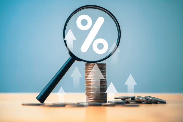 Coins money stacking with up arrow and percentage symbol inside magnifier glass for financial banking increase interest rate or mortgage investment dividend from business growth concept.