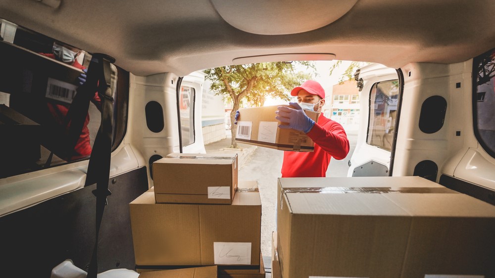 A courier takes packages out of the back of a van.