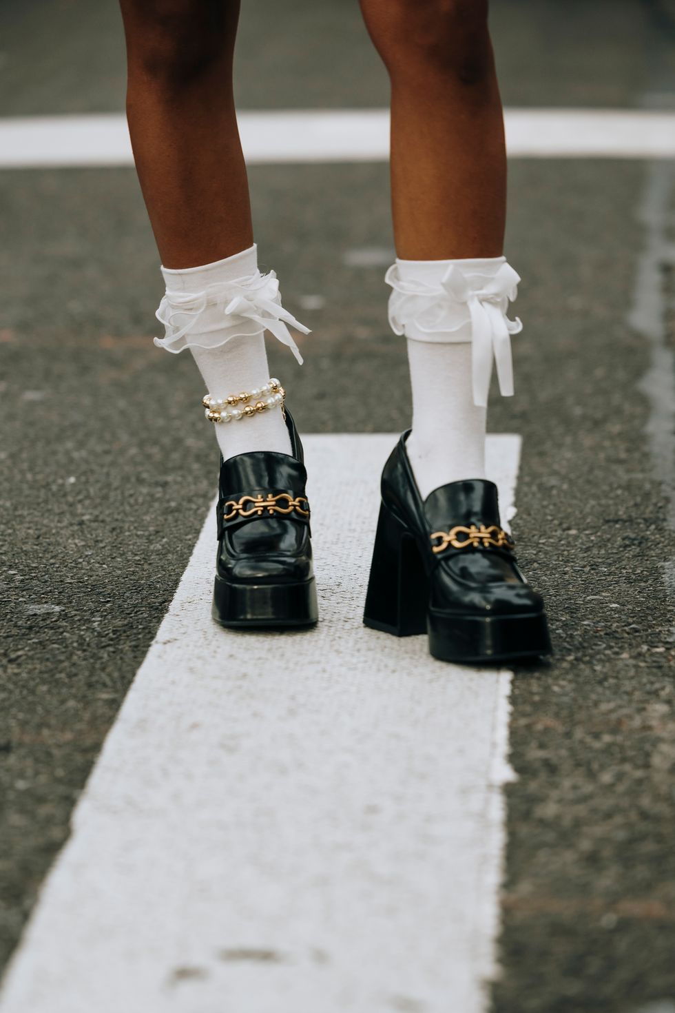 a person's legs with white socks and black shoes