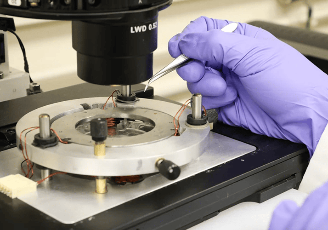 A hand in a purple medical glove using a nanoscalpel.