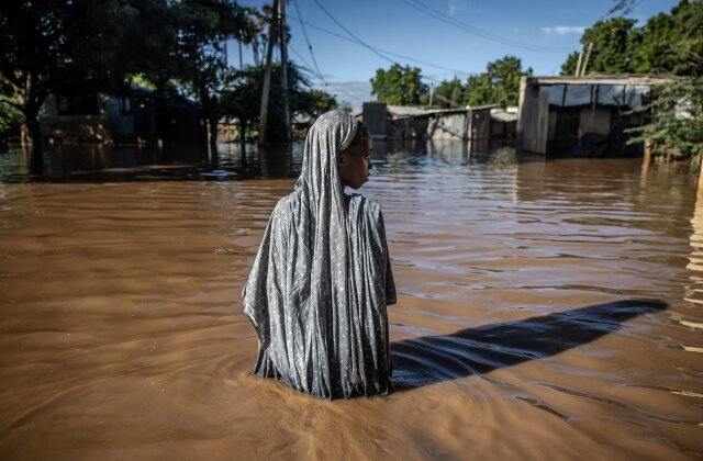 TOPSHOT - A woman wades through flood waters at an inundated residential area in Garissa, on May 9, 2024. Kenya is grappling with one of its worst floods in recent history, the latest in a string of weather catastrophes, following weeks of extreme rainfall scientists have linked to a changing climate. At least 257 people have been killed and more than 55,000 households have been displaced as murky waters submerge entire villages, destroy roads and inundate dams. (Photo by LUIS TATO / AFP) (Photo by LUIS TATO/AFP via Getty Images)