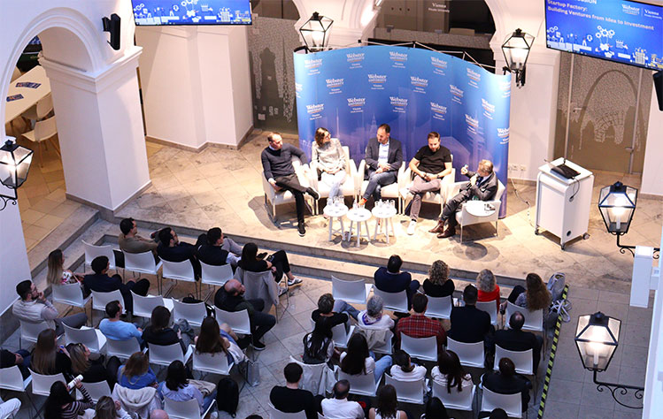 An aerial view of the crowd of attendees listening to the panelists in the atrium of the historic Palais Wenkheim.