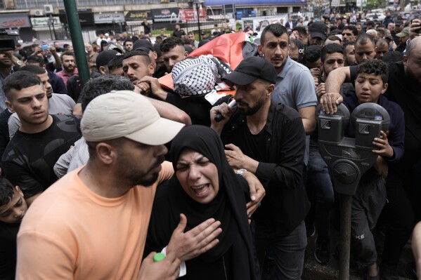 FILE - Mourners carry the body of Samer Rumaneh, draped in a Palestinian flag, who was killed in an Israeli military raid, during his funeral in the West Bank city of Nablus, on May 12, 2024. An AP analysis of Gaza Health Ministry data finds the proportion of Palestinian women and children being killed in the Israel-Hamas war appears to have declined sharply. Israel faces heavy international criticism over unprecedented levels of civilian casualties in Gaza. (AP Photo/Majdi Mohammed)