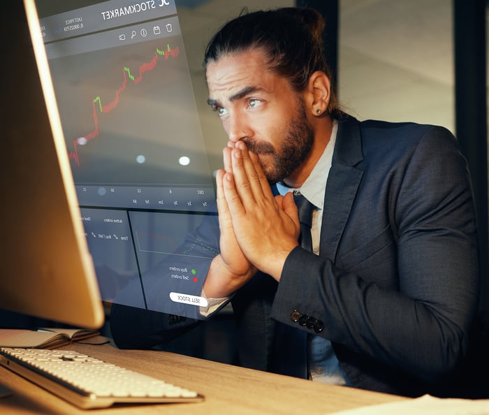 A person looks nervously at a chart on a computer screen.