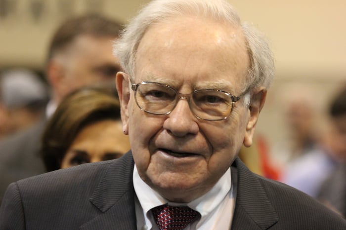 Warren Buffett surrounded by people at Berkshire Hathaway's annual shareholder meeting.