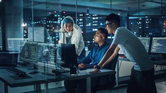 Three cybersecurity professionals working at a workstation.