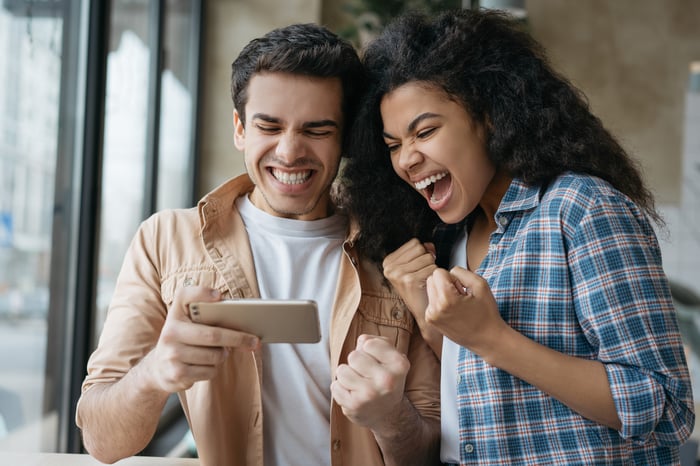 Two investors excited about something on a cellphone.