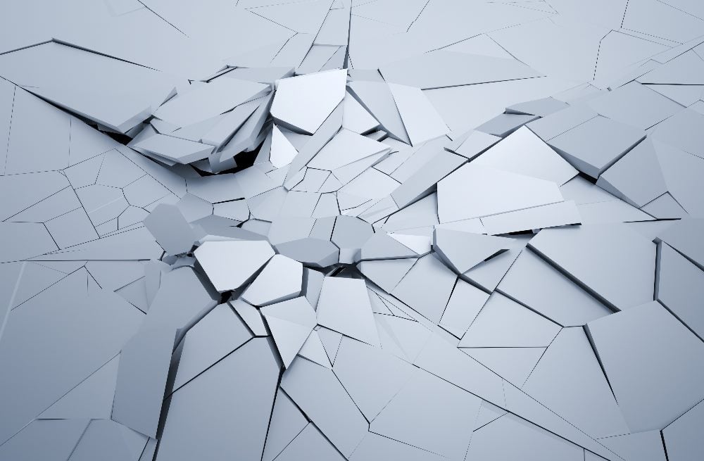 An image of a cracked, fragmented surface with irregularly shaped, angular pieces breaking apart. The surface appears to be a smooth, solid material, and the cracks radiate outward from a central point, suggesting disruption and instability. The overall color is a muted, cool gray, creating a stark and abstract visual representation of structural breakdown in piece about the impact of generative AI on the online economy.