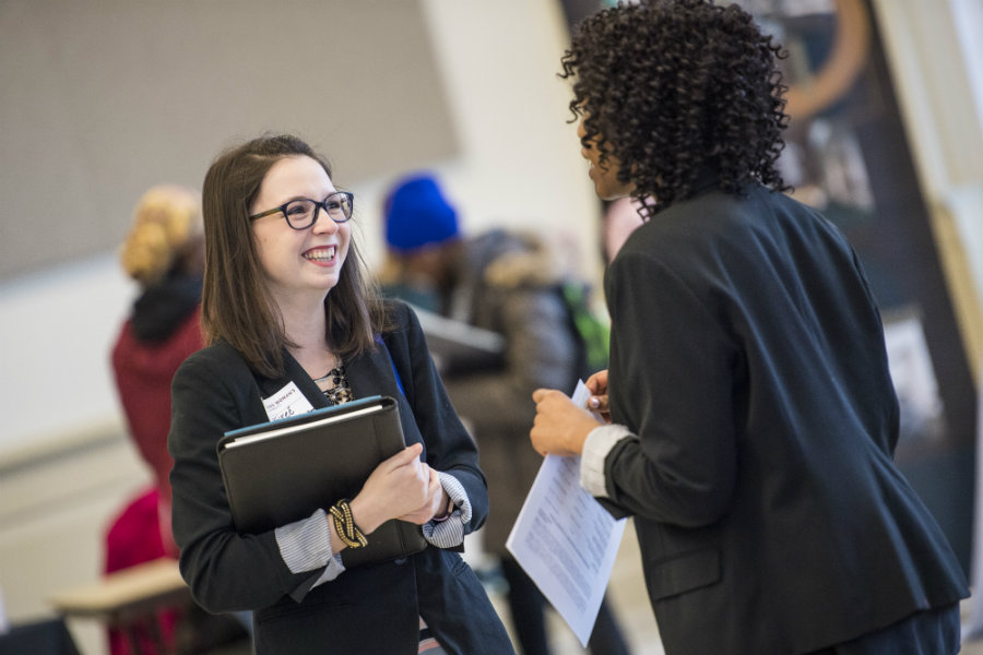 Two women in business casual talking and networking.