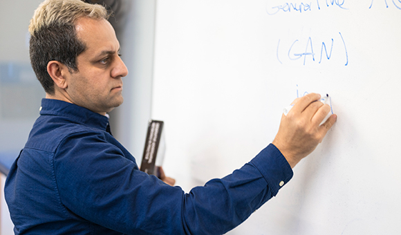 Mehdi Ghayoumi writes on a marker board.