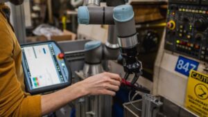 An employee monitors a Precision Cobotics robot as it unloads screws from a machine. PHOTO/PRECISION COBOTICS