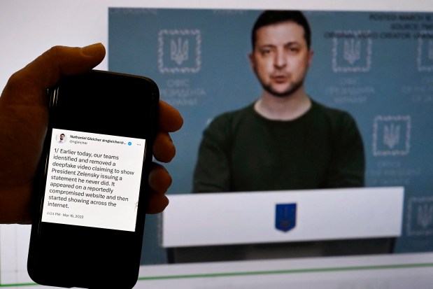 In this photo illustration, a phone screen displays a statement from the head of security policy at META is seen in front of a fake video of Ukrainian President Volodymyr Zelensky calling on his soldiers to lay down their weapons. (Photo by OLIVIER DOULIERY/AFP via Getty Images)