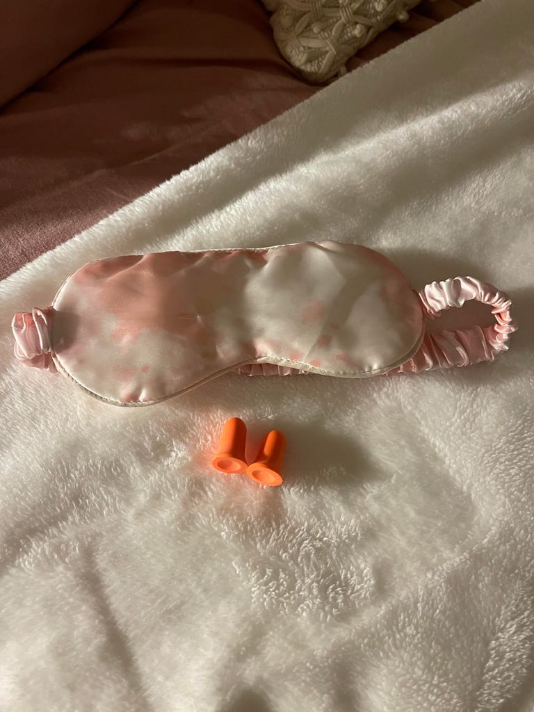 Portrait of a sleep eye mask and a pair of earplugs.