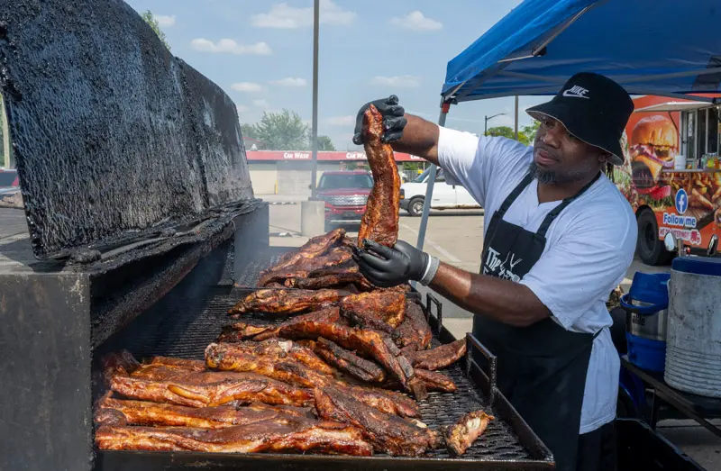 Raymond Barbour stands at his BBQ pit cooking food.