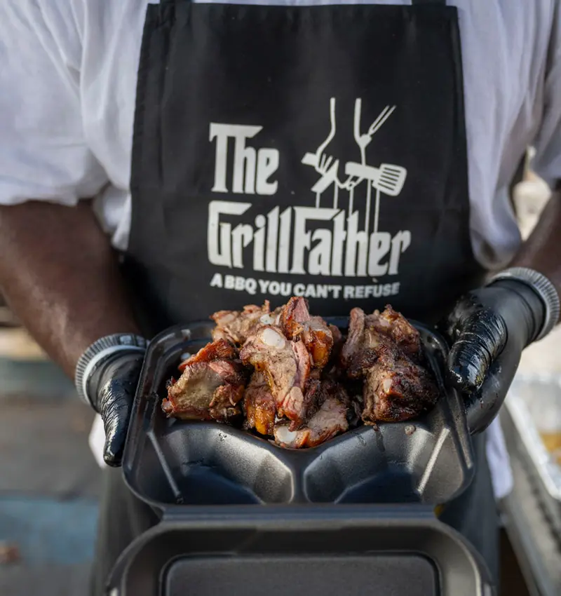 A close up of Raymond Barbour's holding a styrofoam container of BBQ. 