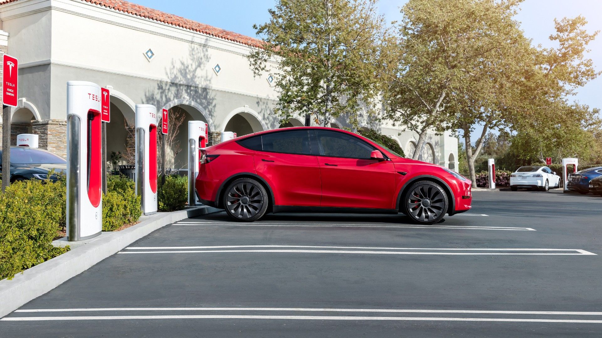 Red Tesla Model Y Charging At A Tesla Supercharger